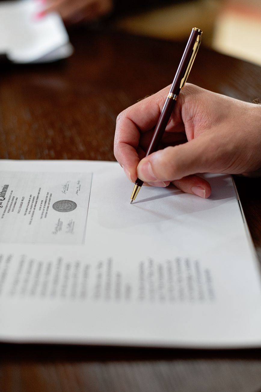a close up shot of a person signing a document